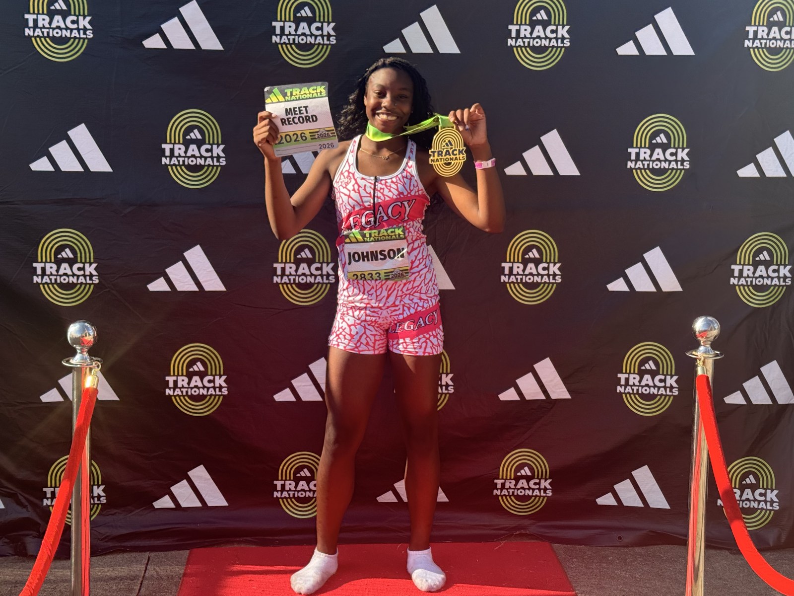 Zoei Johnson holding her Track Nationals meet record card and gold medal